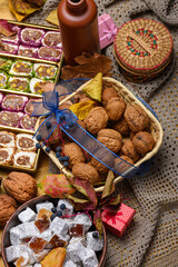 Assorted oriental sweets with pistachio turkish delight rolls, walnuts, and pomegranate lokum. Festive seasonal display with autumn leaves and gift boxes on a wooden background.