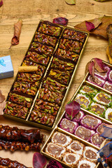 Assorted oriental sweets with pistachio turkish delight rolls, walnuts, and pomegranate lokum. Festive seasonal display with autumn leaves and gift boxes on a wooden background.
