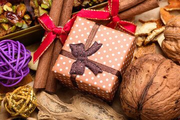 Christmas gift box with walnuts and cinnamon sticks on festive wooden background