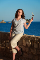 Serene young woman holding sunglasses and looking away at the sea, enjoying the summer sunset and freedom on vacation.