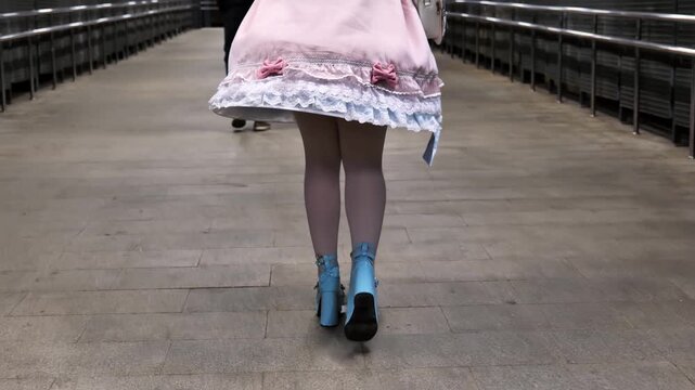 Lolita fashion lover walking in the city with pastel pink dress and blue platform heels