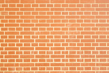 Naklejka premium Textured red brick wall with evenly spaced bricks and mortar joints, showcasing a uniform pattern and warm color tones in a solid construction material