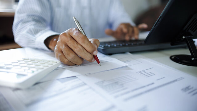 close up shot, accountant working with computer reviewing the company's accounts and financial documents on desk
