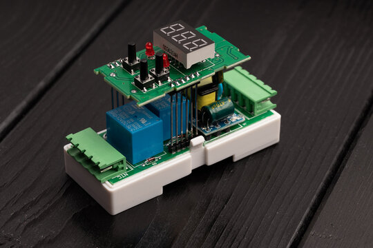 Electronic device with components and a 7-segment display mounted on a plastic casing, on a wooden surface.