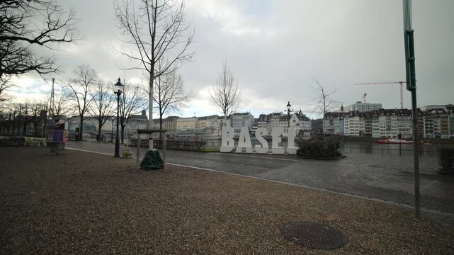 Large white Basel city sign on the Rhine river bank with cityscape background with pan, Switzerland.