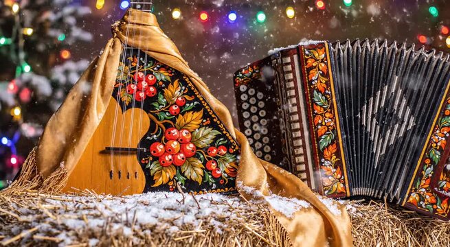Russian folk music instruments balalaika and accordion on hay in winter. Seasonal celebration with festive light garland. Cultural event concept.
