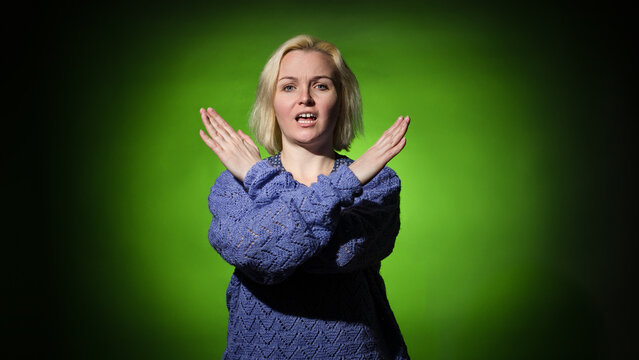a woman in blue on a green spot asks to stop showing a sign with her hands