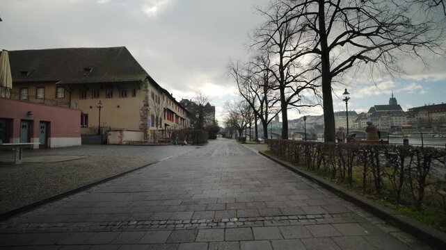 Scenic riverside path with pan along the Rhine with historical buildings and cityscape in Basel, Switzerland.