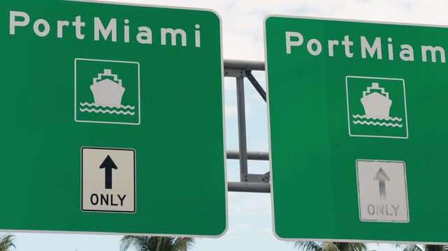 Green road signs directing traffic to Port Miami cruise terminals, highlighting maritime transport access, tourism infrastructure, and coastal travel routes in Miami, Florida.