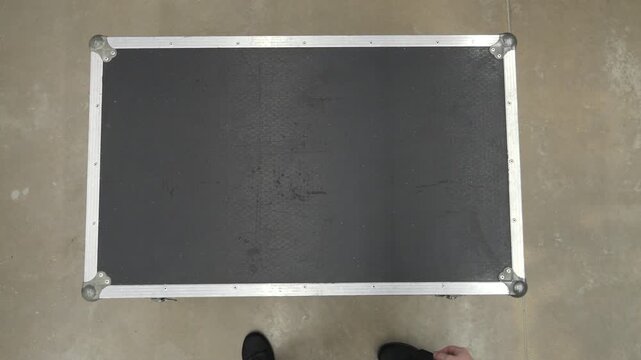 Sound technician opening a flight case trunk from above with audio equipment