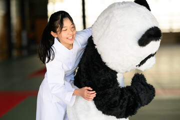 道場でパンダの着ぐるみに抱きつく空手着の女の子　ユニークな交流イベント