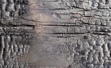 charred wooden surface, showing deep cracks, burned textures, and layers of blackened wood and charcoal background