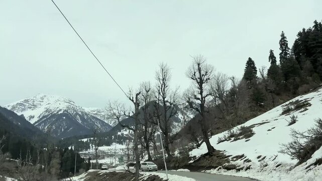 Scenic road and pathway leading to Aru Valley surrounded by lush meadows, pine forests, rivers, and Himalayan mountain landscapes near Pahalgam, Kashmir.