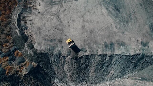 Open pit mine with unloading dump truck, extractive industry for coal, top view aerial.