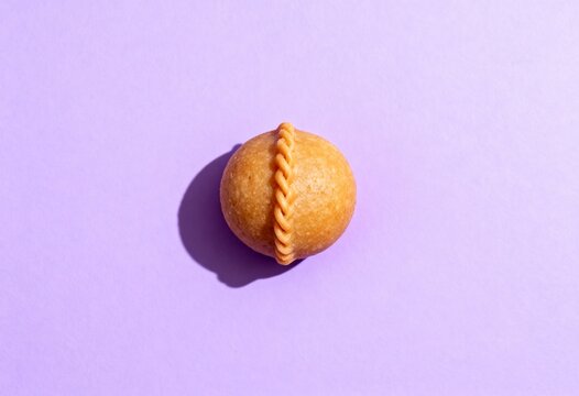 A traditional Indian Gujiya sweet for the Holi festival. Minimalist flat lay of a single pastry on a purple background with hard light. Asian dessert and celebration food concept with copy space