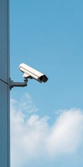 Surveillance camera mounted on building against clear blue sky