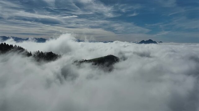Cinematic flight over thick rolling clouds with distat mountain peaks