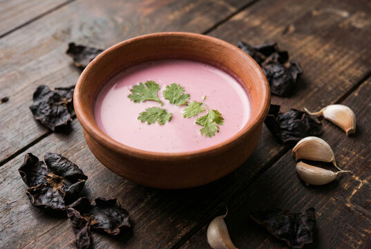 Pink Solkadhi digestive drink in a clay bowl with kokum skins and garlic
