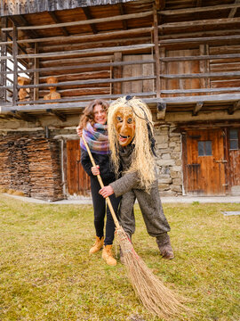 A woman hugs a person in a traditional witch costume holding a broom, the famous Kheirar. Sauris,Friuli Venezia Giulia,Italy