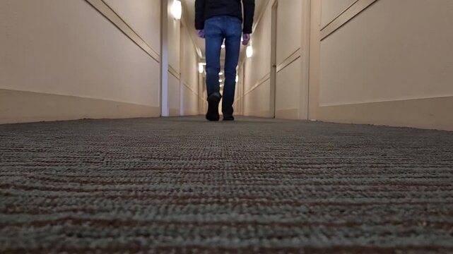 Man walking away down long corridor filmed from floor level