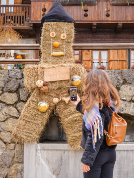 in the traditional Sauris mountain Carnival, A woman takes a photo of a straw figure with a sign that reads "Der R&ouml;lar". Sauris,Friuli Venezia Giulia,Italy