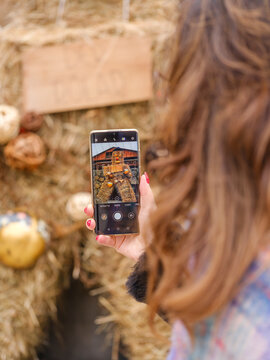 in the traditional Sauris mountain Carnival, Woman taking a photo of a straw figure with a smartphone. Sauris,Friuli Venezia Giulia,Italy