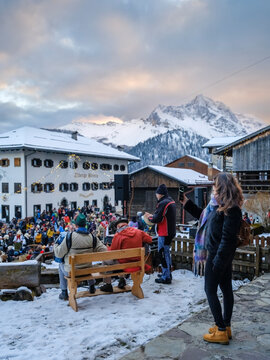 in the traditional Sauris mountain Carnival, Outdoor winter scene with a crowd watching musicians perform in front of snow-covered buildings and mountains. Sauris,Friuli Venezia Giulia,Italy