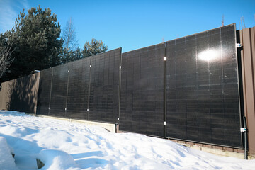 Solar panels covered in ice and icicles on a sunny winter day
