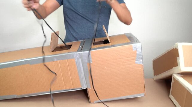 Artist adding plastic raffia to carbdoard box crafts