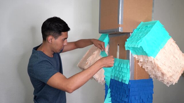 Man attaching blue craft paper to cardboard arts figure