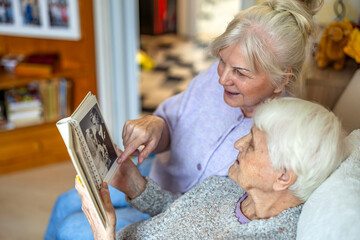 Senior woman looking at old photos with her caregiver
