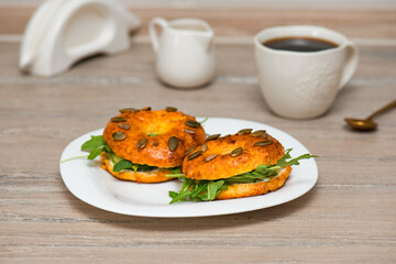 Homemade bagels with curd cheese, fish and arugula and coffee drink.