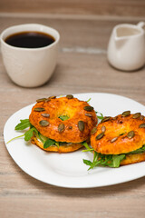 Bagels with curd cheese, fish and arugula in a plate with cup of coffee. Homemade breakfast. Vertical orientation.