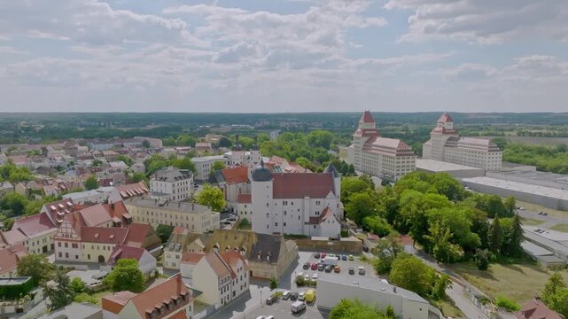 View over the UNESCO World Heritage old town of Bamberg. The characteristic red tiled roofs and historic streets stretch out in front of the forested hills of the Steigerwald under a clear spring sky.