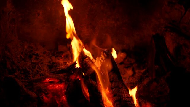 Bright campfire burning in deep darkness with flickering flames illuminating night. perfect for travel films, relaxation visuals, survival themes, motivational content, atmospheric background use