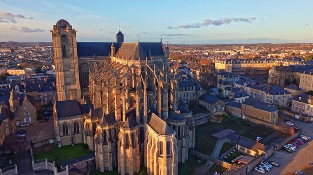 Wide aerial establishing shot of Saint Julien Cathedral dominating cityscape of Le Mans at sunset in France. Aerial drone sideways