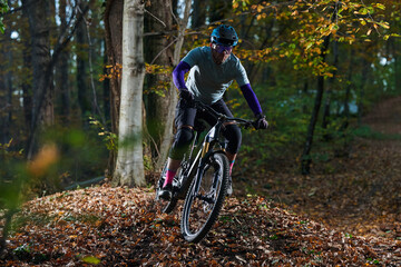 Autumn Forest Mountain Biker Navigates Leaf-Covered Trail with Speed and Focus