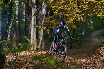 Naklejka premium Mountain Biker Navigates Autumn Forest Trail With Focus, Gear, And Speed