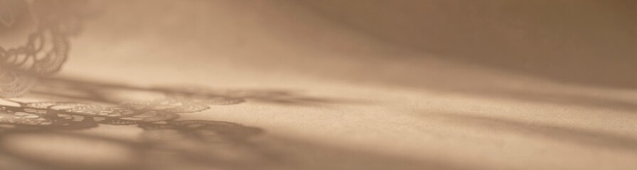 Delicate lace shadow on soft beige surface