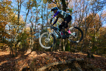 High-Flying Mountain Biker Jump Over Leafy Trail in Autumn Forest Adventure
