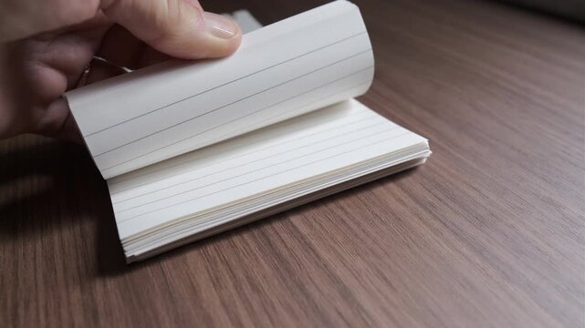 Hand leafing through diary on wooden table