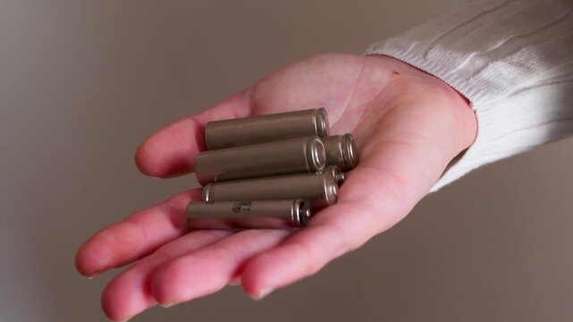 Human hand presenting multiple finger batteries neutral background, conveying functionality, utility, portable energy solutions. concept small electronics, household devices, technological lifestyle