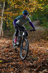 Autumn Mountain Biker Navigates Leaf-Litter Trail Through a Forest Path in Autumn Colors