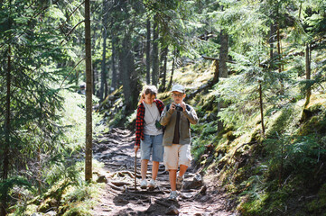 Obraz premium Tourists hiking in forest, children exploring nature with camera