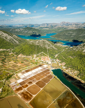 Aerial view of the contrasting terraced salt pans against the turquoise waters and rugged mountains, Ston, Dubrovnik-Neretva County, Croatia.