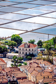 View of a historic town with red-tiled roofs nestled beneath shimmering salt pans reflecting the sky, a beautiful contrast of color and texture, Ston, Dubrovnik-Neretva County, Croatia.