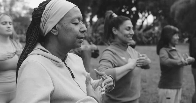 Multiracial women doing yoga focus exercise outdoor at city park - Multi generational people, healthy lifestyle and group concept - Black and white editing