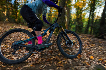 Fototapeta premium Mountain Bike Rider Races Through Autumn Forest Trail With Pink Socks And Rugged Gear