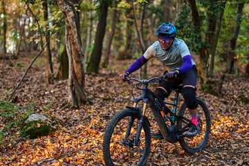 Mountain Biker Races Through Autumn Forest Trail in Protective Gear and Focused Expression