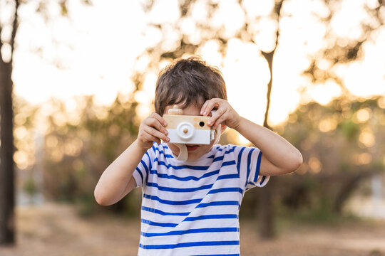 Child holding wood camera toy playing outdoors